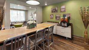 A modern dining area with a wooden table, metal chairs, and a coffee machine. - WoodSpring Suites Quantico (Stafford)