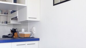 A modern kitchen with white cabinets, a blue countertop, and a black leather couch. - Playa Blanca (La Serena)