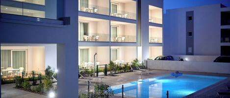 Ein modernes Hotel mit Pool auf dem Dach, mehreren Balkonen und Sitzbereichen im Freien.