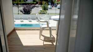 Blick vom Balkon mit Holzboden, weißem Tisch und zwei weißen Stühlen.