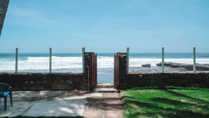 Un sentier menant à une plage avec vue sur l’océan, un mur de pierres et un portail en métal.
