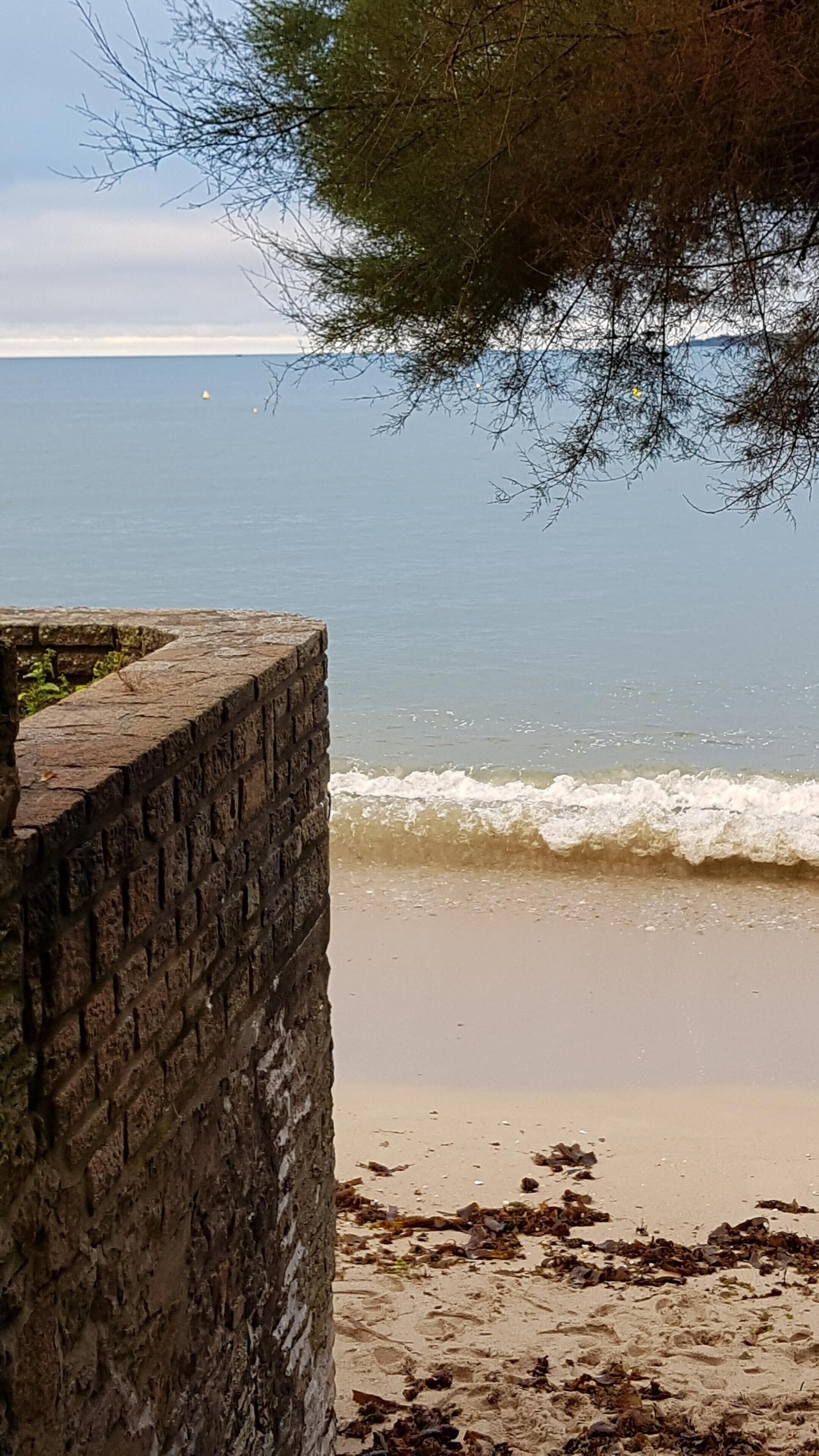 Een strand met een stenen muur en golven.
