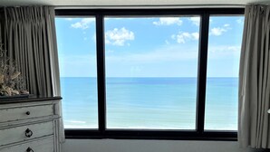 Ein Schlafzimmer mit einem großen Fenster und Blick auf den Ozean.