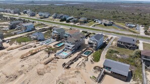 A coastal residential area with multiple houses, a beach, and a road. - 5849- Mari-Time, Oceanfront 8BR Luxury: Theater, Pool & Elevator (South Nags Head)
