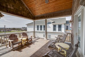 Relax in a serene outdoor space with Adirondack chairs and a small table, surrounded by a white railing and breathtaking views.