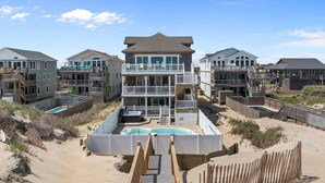 A beachfront property with multiple buildings, a central pool, and wooden walkways. - 5849- Mari-Time, Oceanfront 8BR Luxury: Theater, Pool & Elevator (South Nags Head)