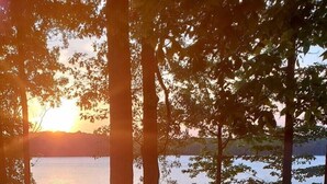 Une vue sur le lac, avec des chaises et une table, le tout entouré d’arbres.