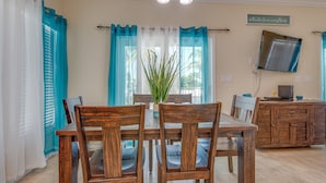 A dining area with wooden chairs and a table, a potted plant, and a television on a cabinet. - Keys Cove Villas - No 1 (Marathon)