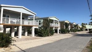 A row of beachfront houses with balconies, a gravel driveway, and palm trees. - Keys Cove Villas - No 1 (Marathon)