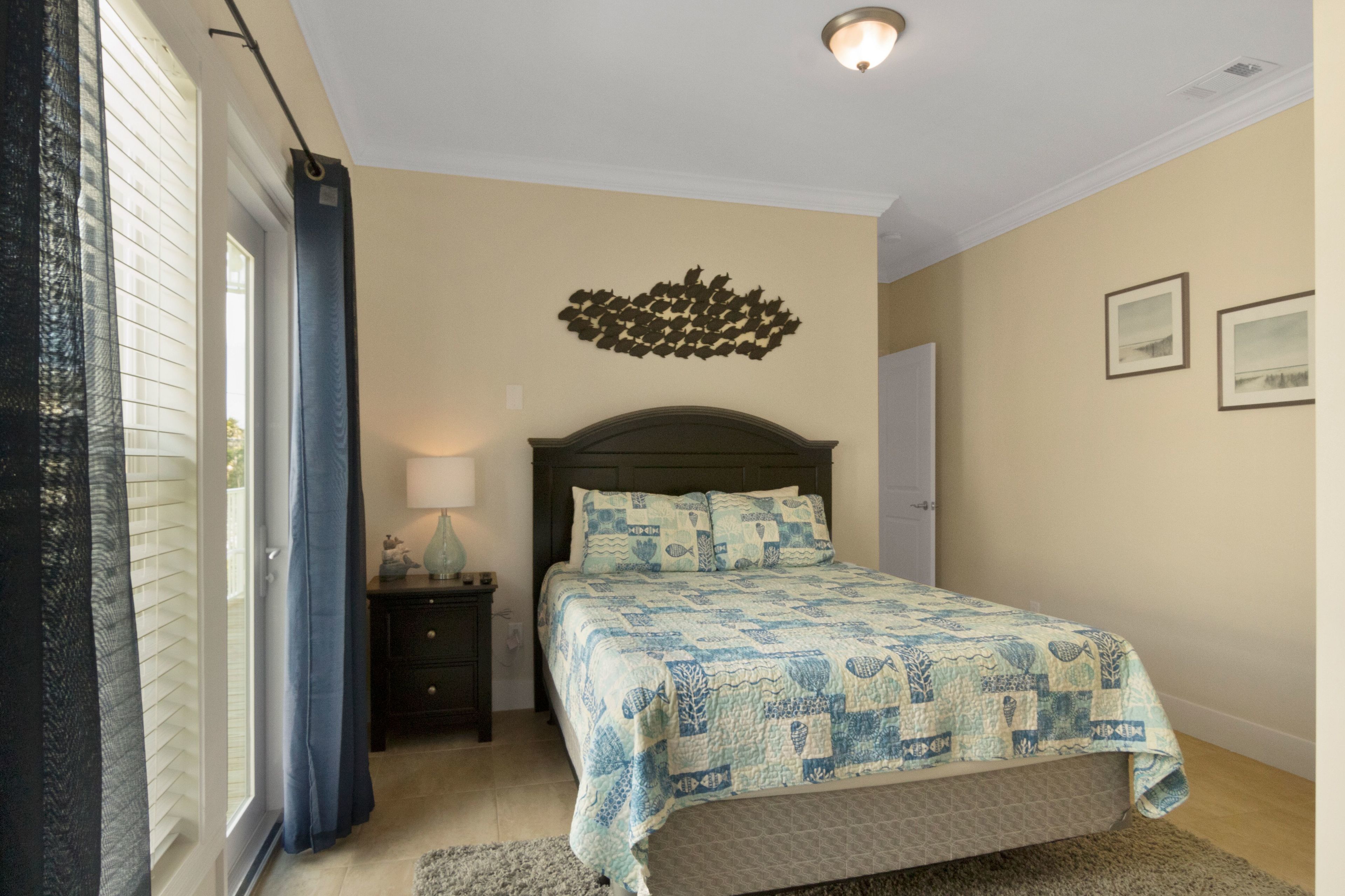 Une chambre à coucher comprenant un lit, une table de chevet, une lampe, une fenêtre avec des rideaux et un élément de décoration murale.