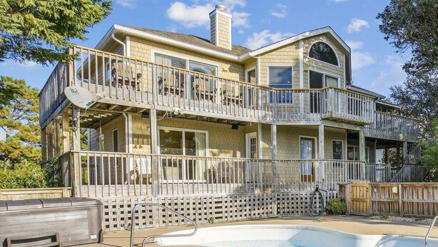 A two-story house with a balcony, a swimming pool, and a fenced backyard. - 1537 - Carolina Sunset - Soundside Sunsets w/ Pool, Hot Tub & Game Room (Corolla)