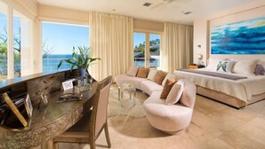 Uma sala de estar espaçosa com uma grande janela, sofá, mesa de jantar e uma cama com vista para o mar.
