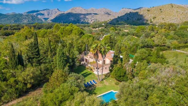 An aerial view of a villa surrounded by dense greenery and mountains.