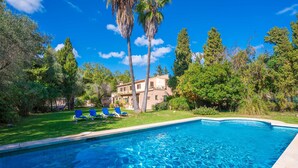 A swimming pool with clear blue water, surrounded by a well-maintained lawn and trees.