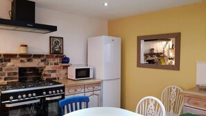 Enjoy cooking in the fully equipped kitchen with a brick wall stove, microwave, and refrigerator.