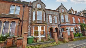 A row of terraced houses with distinct architectural features, including bay windows and stone facades. - Flintrock House -  a house that sleeps 9 guests  in 5 bedrooms (Sheringham)