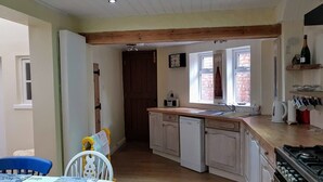 A compact kitchen with a dishwasher, a sink, and a stove. There is a window providing natural light and a clock on the wall. - Flintrock House -  a house that sleeps 9 guests  in 5 bedrooms (Sheringham)