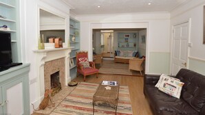 A living room with a fireplace, a television, a sofa, and a coffee table. - Flintrock House -  a house that sleeps 9 guests  in 5 bedrooms (Sheringham)