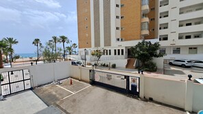 Une entrée sécurisée donnant accès à un immeuble résidentiel, avec vue sur la plage et les palmiers.