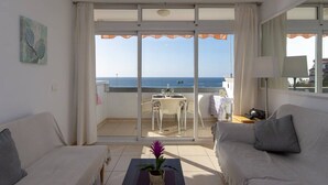 Un balcon avec une table et des chaises, donnant sur la mer.