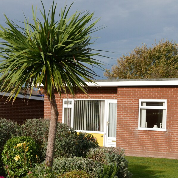 A residential building with a brick exterior, a white door, and a window with a white frame. - 35 Siesta Mar -  a holiday chalet that sleeps 4 guests  in 2 bedrooms (Norwich)