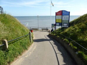 A coastal walkway with a signboard, a flag, and a bench. - 35 Siesta Mar -  a holiday chalet that sleeps 4 guests  in 2 bedrooms (Norwich)