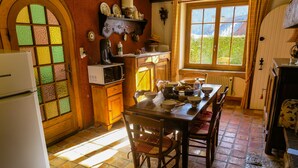 Una cocina con suelo de baldosas, armarios de madera, un refrigerador, un microondas y una mesa de comedor con sillas.