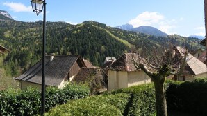Un pueblo rural con casas tradicionales, una farola y montañas al fondo.