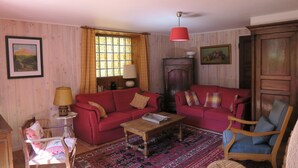 Una sala de estar con dos sofás rojos, una mesa de centro de madera, un tapete estampado y un aparador de madera.