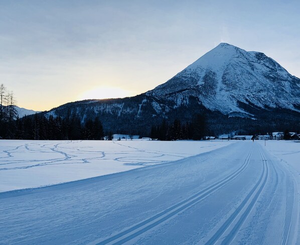 A snow-covered road with tire tracks leading towards a mountain.