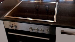 A kitchen with a black countertop, a built-in oven, and a window with a view of a wooden deck. - for two Holidays in an organic wooden house - in harmony with nature (Leutasch)