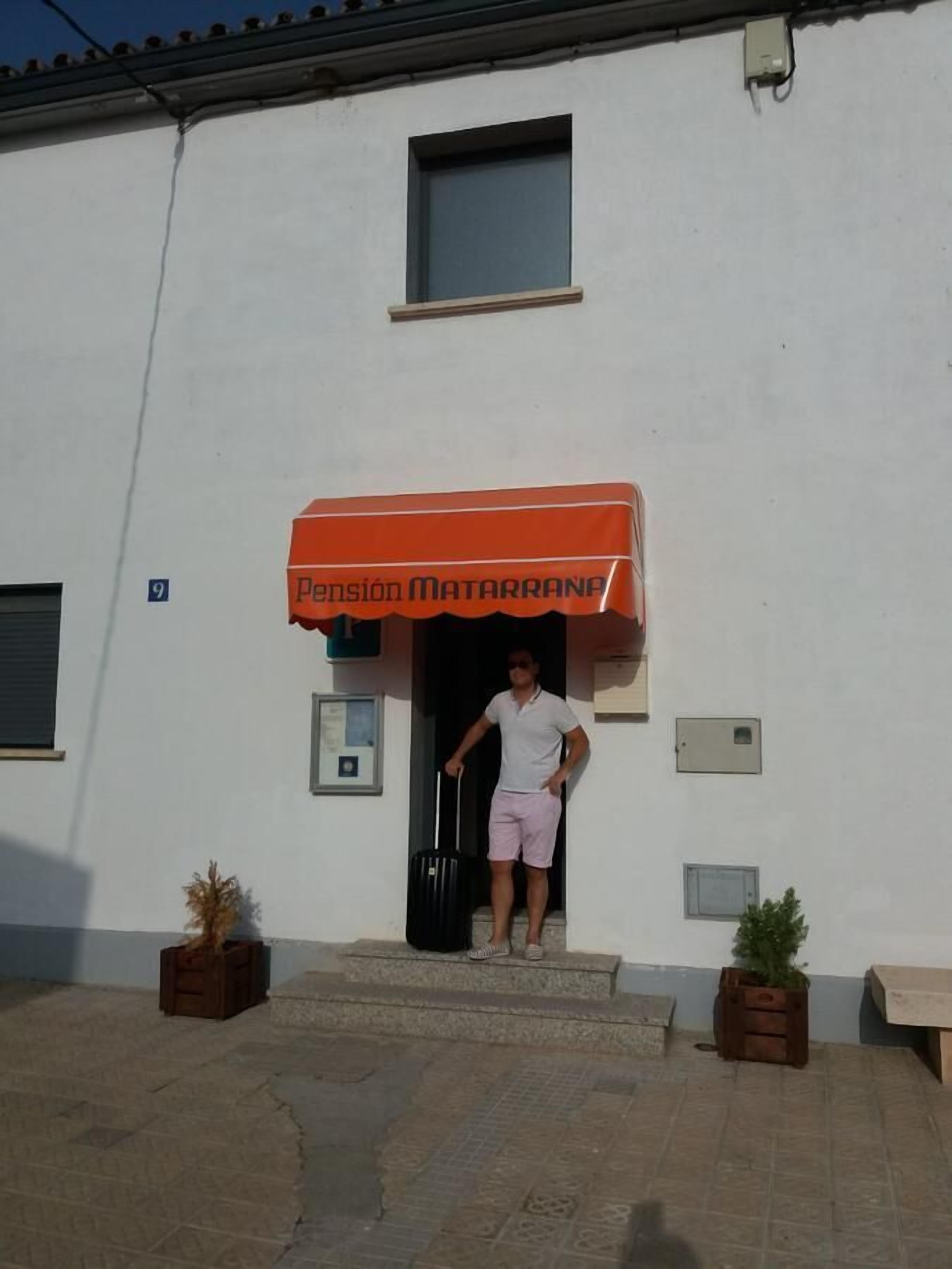 A person exiting a building with a sign reading "Pension Matarrana" above the entrance.