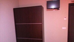 Une pièce avec un placard, un téléviseur fixé au mur et une porte.