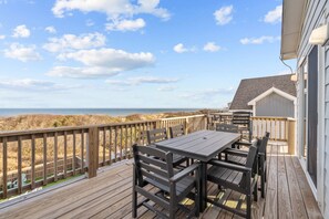A wooden deck with a table and chairs, overlooking a beach and dunes. - 1661 - The Best Nest - Oceanfront Corolla | Pool, Putt-Putt & Hot Tub (Corolla)