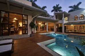 Un espace aménagé au bord de la piscine, avec une terrasse en bois, une piscine et un coin repas comprenant une table et des chaises.