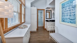 A narrow hallway with a white bench, a white dresser, and a framed artwork on the wall. - 2304 - High Spirits - Pine Island Retreat | Pool, Hot Tub, Near Beach (Corolla)