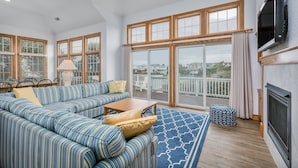 A spacious living room with a large sectional sofa, a wooden coffee table, and a patterned rug. - 2304 - High Spirits - Pine Island Retreat | Pool, Hot Tub, Near Beach (Corolla)