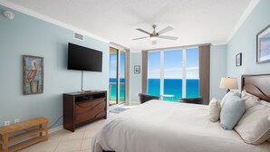 A bedroom with a large bed, a flat-screen TV, a ceiling fan, and a view of the ocean. - Awesome East Side Condo- Sea Forever (Navarre)