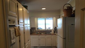 A kitchen with white cabinets, a refrigerator, a microwave, and a sink.