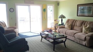 A living room with a sofa, chairs, a coffee table, and a door leading to an outdoor area.