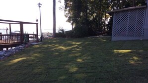 A grassy yard with a wooden deck and a lattice fence.