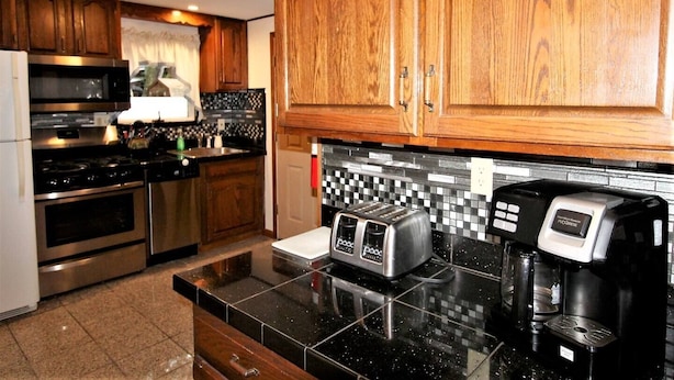 A kitchen with wooden cabinets, a microwave, a toaster, and a coffee maker. - Cooperstown Baseball Rentals - Lakeview Pines (Maryland)