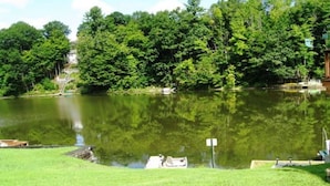 A lake with a dock, surrounded by trees and a grassy area. - Cooperstown Baseball Rentals - Lakeview Pines (Maryland)