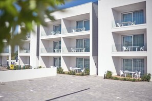A modern multi-story hotel with balconies, outdoor seating, and a paved courtyard. - West Village Appartamento - NUOVO con piscina (Jesolo)