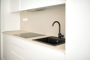 A modern kitchen with a black sink, a beige countertop, and white cabinetry. - West Village Appartamento - NUOVO con piscina (Jesolo)