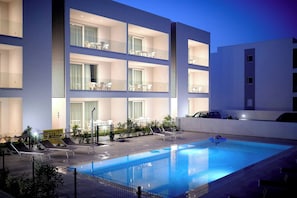 A modern hotel with a swimming pool, multiple balconies, and outdoor seating areas. - West Village Appartamento - NUOVO con piscina (Jesolo)
