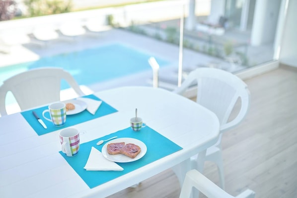 A table with a blue placemat, a plate with toast, a mug, and a cup. - West Village Appartamento - NUOVO con piscina (Jesolo)