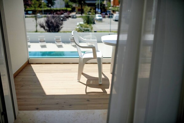 A view from a balcony with a wooden floor, a white table, and two white chairs.