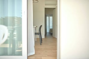 A hallway with wooden flooring, a chair, and a table. - West Village Appartamento - NUOVO con piscina (Jesolo)