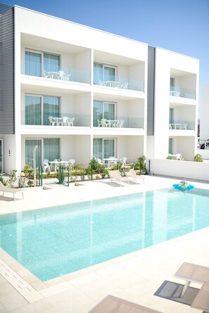 A modern hotel with a rooftop pool, outdoor seating, and multiple balconies. - West Village Appartamento - NUOVO con piscina (Jesolo)